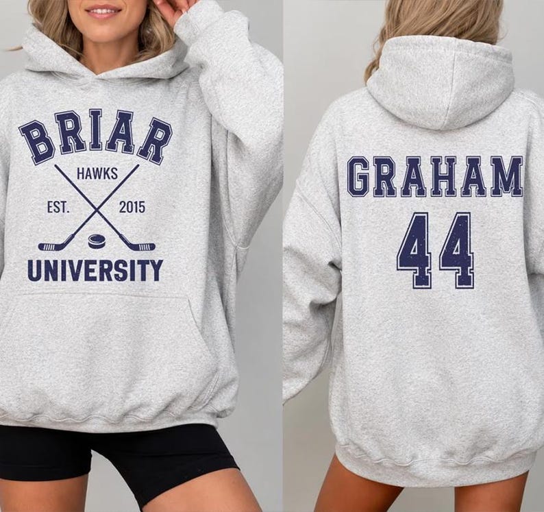 May include: Light gray hoodie with a front graphic that reads "Briar University Hawks" with crossed hockey sticks and the year "2015". The back of the hoodie displays the name "Graham" and the number "44" in navy blue.