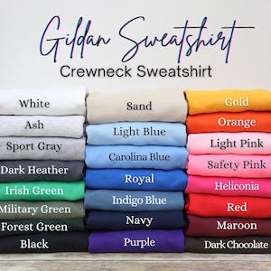 May include: A stack of Gildan crewneck sweatshirts in various colors, including white, black, and navy. The image displays a range of hues, from light pink to dark chocolate, with each color labeled for easy selection.