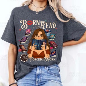 May include: Dark gray t-shirt with the text "Born to Read" above an illustration of a woman reading a book, surrounded by books. The phrase "Forced to Work" is below the illustration.