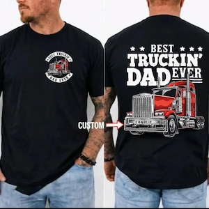 May include: A black t-shirt featuring a red semi-truck graphic on the front left chest and a larger version on the back. The back graphic includes the text "BEST TRUCKIN' DAD EVER" and a license plate reading "CHARLIE" on the red truck front.
