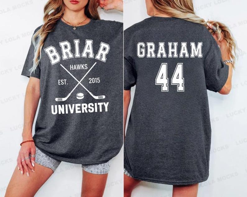May include: Dark gray t-shirt with white text and graphics. The front features "BRIAR HAWKS UNIVERSITY" with crossed hockey sticks and a puck. The back displays "GRAHAM 44".