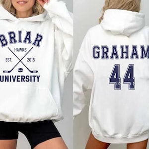 May include: White hoodie with navy blue text and graphics. The front features "Briar Hawks University" with crossed hockey sticks and a puck. The back displays "Graham" and the number "44".