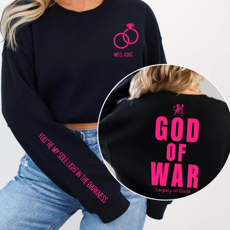 May include: Black sweatshirt with pink text and graphics. Features a diamond ring graphic and the text "MRS. KING". The left sleeve has the text "YOU'RE MY SOLE LIGHT IN THE DARKNESS". The back has "GOD OF WAR" and "Legacy of Gods".