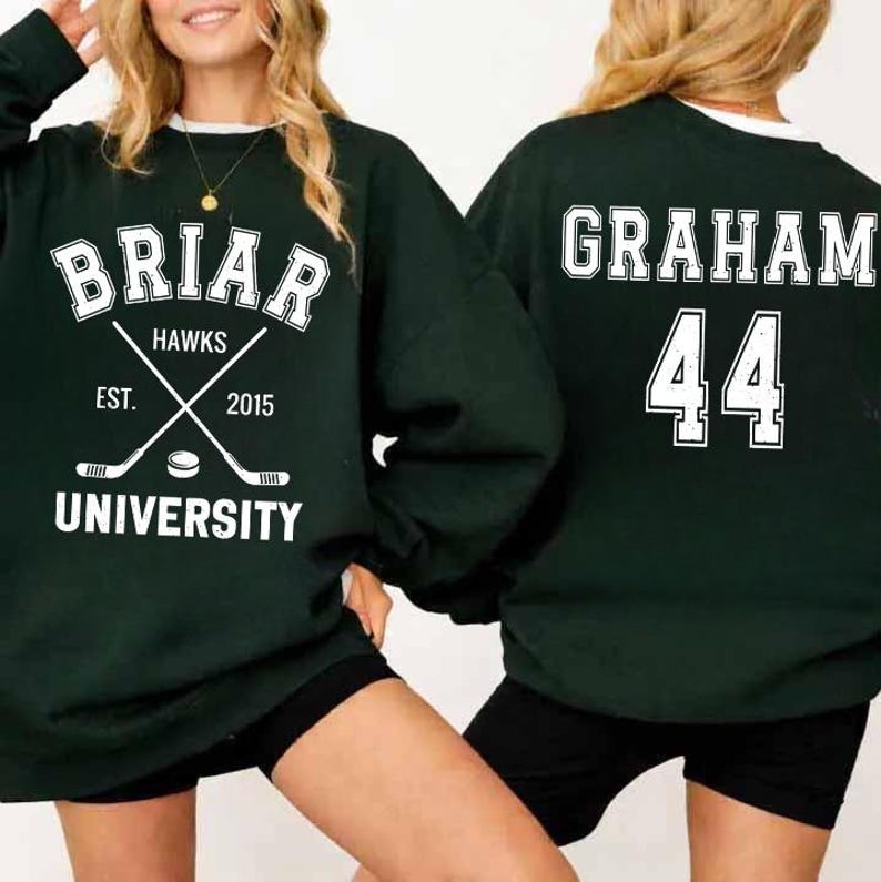 May include: Dark green sweatshirt with white lettering. The front features "Briar Hawks University" with crossed hockey sticks and a puck. The back displays "Graham 44". The sweatshirt has a white collar.