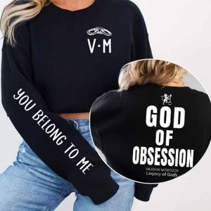 May include: Black sweatshirt with white text and graphics. The left sleeve reads "YOU BELONG TO ME." The front features "V&bull;M" and a chain graphic. The back displays "GOD OF OBSESSION" and "VAUGHN MOROZOV Legacy of Gods."
