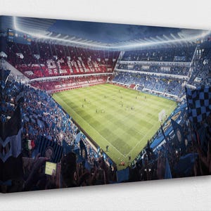 Könnte beinhalten: Leinwanddruck eines Fußballstadions voller Fans. Die Tribünen sind mit Zuschauern gefüllt, die Fahnen schwenken. Das Spielfeld ist grün und das Stadion wird von hellen Lichtern beleuchtet. Die Teamfarben sind Rot und Blau.
