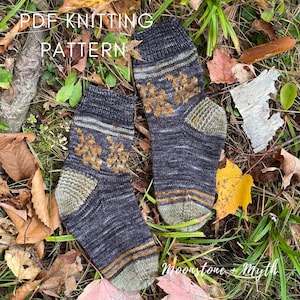 May include: A pair of knitted socks with a brown, green, and gold color scheme. The socks feature a leaf pattern and the text "PDF Knitting Pattern" and "Moonstone + Myth".
