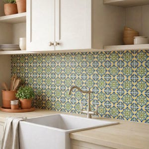 May include: A kitchen backsplash featuring square tiles with a repeating blue, yellow, and green floral pattern. The tiles are installed behind a white farmhouse sink with a metal faucet, set against light-colored cabinets and wooden countertops.