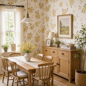 May include: A dining room featuring a wooden table with four spindle-back chairs, a light-colored table runner, and a white vase with yellow flowers. A wooden sideboard stands against a wall with floral wallpaper, topped with a lamp and framed art.