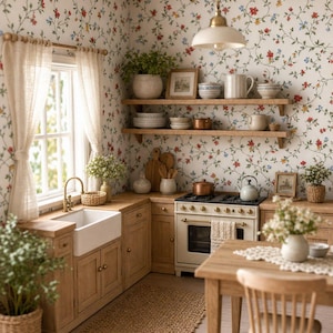 May include: A miniature kitchen scene featuring floral wallpaper, light wood cabinetry, a white farmhouse sink, and a gas range. The space includes open wooden shelving with ceramic bowls, a dining table with a chair, and potted greenery throughout.