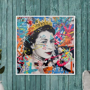 May include: A framed pop art portrait of Queen Elizabeth II, with a crown and red lipstick, set against a backdrop of colorful graffiti. The artwork includes the text "Royal Family" and various other artistic elements.