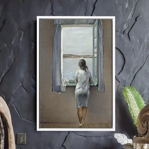 Peut inclure: Une peinture encadrée représente une femme regardant par une fenêtre une étendue d'eau. La femme porte une robe blanche et se tient près d'un rideau bleu. La peinture est placée contre un mur sombre et texturé. Un pouf gris à franges est devant le mur.