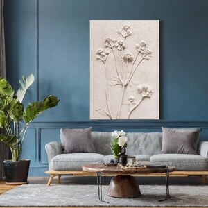 Puede incluir: Una obra de arte en relieve floral beige cuelga sobre un sof&aacute; gris. La obra de arte presenta una representaci&oacute;n detallada de varias flores con largos tallos. La habitaci&oacute;n tiene paredes azules, una alfombra gris y una gran planta en maceta.