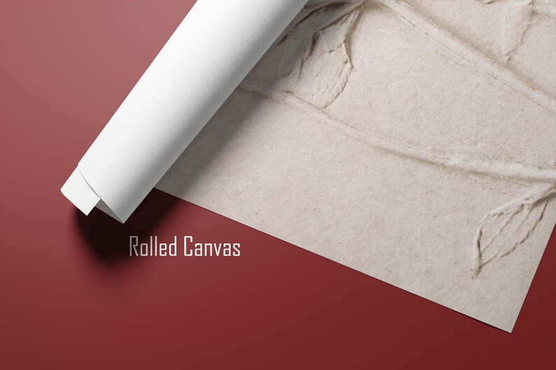 Puede incluir: Impresi&oacute;n en lienzo enrollado con una superficie beige texturizada, parcialmente desenrollada para revelar un dise&ntilde;o floral detallado. La parte enrollada es blanca, contrastando con el fondo rojo-marr&oacute;n. El texto "Rolled Canvas" est&aacute; impreso en blanco.