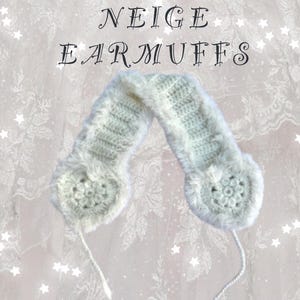 May include: Cream-colored crocheted earmuffs with a fluffy, faux fur trim. The ear coverings have a circular design and are connected by a crocheted band. The text "NEIGE EARMUFFS" is displayed in a decorative font.