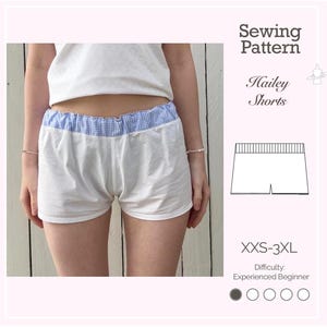May include: White shorts with a blue and white gingham waistband. The shorts are part of a sewing pattern labeled "Hailey Shorts" with sizes XXS-3XL. The difficulty level is listed as "Experienced Beginner".