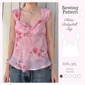 May include: A pink babydoll top with a floral pattern. The top has a square neckline and wide straps. The image also includes a sewing pattern with the text "Olivia Babydoll Top" and size range XXS-3XL.