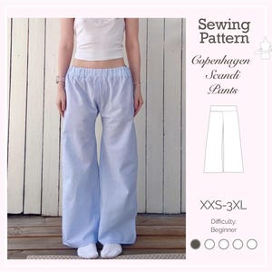 Puede incluir: Pantalones a rayas azules y blancas con diseño de pernera ancha. La imagen muestra a una persona que lleva los pantalones. También se ve un patrón de costura con el texto "Copenhagen Scandi Pants" y tallas XXS-3XL. Dificultad: Principiante.