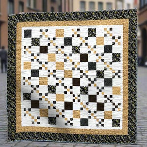 May include: A handmade quilt with a geometric pattern. The quilt features alternating squares of white, black, and tan fabrics. The border is a black floral print, with a gold and tan inner border. The quilt is displayed outdoors.