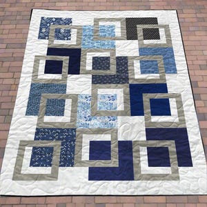 Puede incluir: Un edredón hecho a mano con un diseño geométrico de cuadrados y rectángulos. El edredón utiliza azules, blanco y gris, con patrones florales y de lunares. El edredón mide aproximadamente 152 cm por 203 cm.