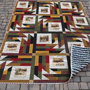May include: A patchwork quilt with a geometric design in shades of green, red, black, and gold. The quilt features square panels with winter landscape scenes. The reverse side has a blue and white striped pattern.