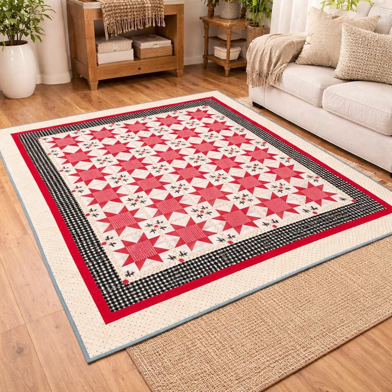 May include: A large, rectangular quilt with a star pattern in red and white. The quilt has a black and white checkered border, a red border, and a cream-colored edge. The quilt is placed on a wooden floor.