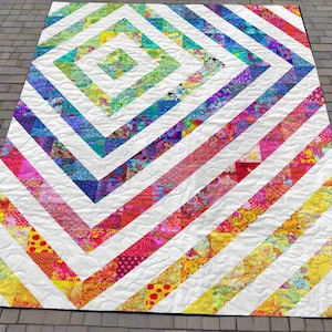 May include: A colorful handmade quilt with a geometric design. The quilt features a central diamond pattern in shades of green, blue, and yellow, surrounded by diagonal stripes in various colors. The stripes are separated by white fabric.