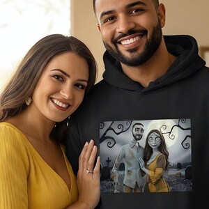 Peut inclure: Un sweat &agrave; capuche noir avec une impression graphique d'un couple dans un cadre effrayant. Une femme en robe jaune se tient &agrave; c&ocirc;t&eacute; d'un homme portant le sweat-shirt. La femme porte une robe jaune. L'arri&egrave;re-plan comprend un canap&eacute;, une lampe et une chemin&eacute;e.