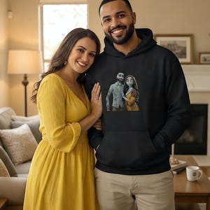 Peut inclure: Un sweat &agrave; capuche noir avec un motif de couple de dessins anim&eacute;s. Une femme en robe jaune et un homme en sweat &agrave; capuche noir sourient. L'arri&egrave;re-plan comprend un salon avec un canap&eacute;, une chemin&eacute;e et une table.
