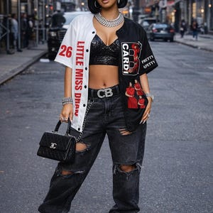May include: A black and white baseball jersey with the text "Little Miss Dran" and "Cardi B" is worn with ripped black jeans and gray sneakers. A black handbag and silver jewelry complete the look.