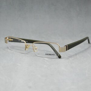 Puede incluir: Gafas con montura de metal dorado y patillas verde oscuro. La parte inferior de las lentes no tiene montura y la marca "Bikkembergs" es visible en la lente. Las gafas tienen forma rectangular.