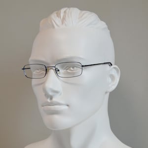 May include: Rectangular eyeglasses with a thin, dark blue frame. The glasses have clear lenses and are displayed on a white mannequin head. The design is simple and modern, suitable for everyday wear.