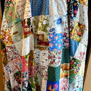 May include: A patchwork quilt coat featuring a variety of floral, fruit, and rooster patterns. The coat is made of numerous fabric squares in various colors, including red, blue, green, and yellow. The coat is a unique piece of wearable art.