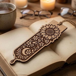 May include: A rectangular wooden bookmark featuring a laser-cut design of a large sunflower at the top, followed by a pattern of small flowers, leaves, and a crescent moon. The bookmark includes a natural twine tassel attached to the top edge.