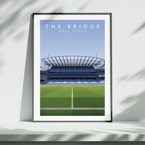 May include: Framed art print of a stadium with the text "THE BRIDGE WEST STAND" at the top. The stadium has blue seating and a green field with white lines. The sky is light blue.