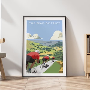 May include: Framed art print featuring cyclists riding through a scenic landscape. The artwork depicts three cyclists in red jerseys on a winding road, with rolling green hills and a blue sky. The text "THE PEAK DISTRICT" is at the top.