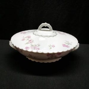 May include: A white ceramic mug with a black handle and the text "But First, Coffee" in a black, handwritten-style font. The mug is on a white surface.