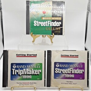 May include: A collection of Rand McNally software CDs, including StreetFinder Deluxe 1998 and TripMaker and StreetFinder 1996 editions. The CDs are in clear cases with colorful labels and text. The products are displayed on small gold-colored stands.