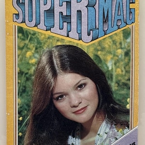 May include: A vintage Super Mag magazine, Vol. 3, No. 12, featuring a portrait of a person with long brown hair on the cover. The yellow cover includes the text SUPER MAG, a $1.00 price, and a purple banner stating IN THE CENTERFOLD: A Valerie Bertinelli mini-poster.