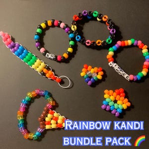 May include: A collection of colorful Kandi bracelets, keychains, and charms. The items are made of small, brightly colored beads arranged in rainbow patterns. Some pieces have text that reads "XD" and "YIPPEE". The image includes the text "RAINBOW KANDI BUNDLE PACK".