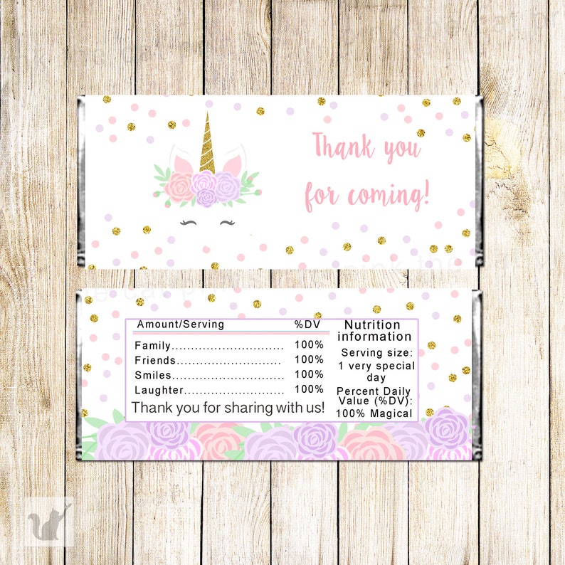 Pu&ograve; includere: Un incarto rettangolare per barretta di cioccolato con sfondo bianco e pois glitterati rosa e oro. Il fronte mostra un volto di unicorno con corno dorato e corona floreale, con il testo Thank you for coming. Il retro mostra un'etichetta nutrizionale.