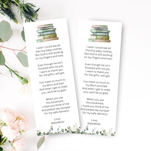 Könnte beinhalten: Zwei weiße Lesezeichen mit einer Illustration eines Bücherstapels und Text. Der Text lautet: "I wish I could see all the tiny baby clothes..." und "Love, BabyMiller." Grüne und rosa florale Akzente befinden sich unten.