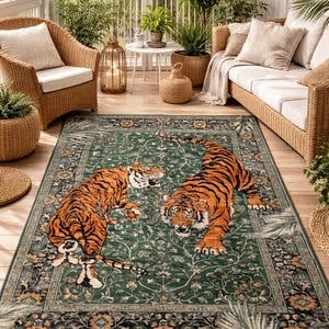 Könnte beinhalten: Ein grüner Teppich mit einem Design, das zwei orange und schwarze Tiger zeigt. Der Teppich hat einen floralen Rand und ein verwittertes Aussehen. Er befindet sich in einem Wintergarten mit Korbmöbeln und Pflanzen. Die Maße des Teppichs sind in Zentimetern.