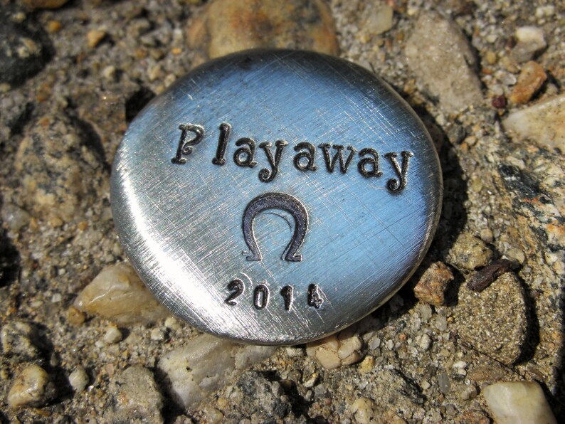 May include: A silver disc with the words "Playaway" and the year "2014" engraved on it. The disc also features an omega symbol.