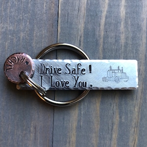 May include: Silver keychain with a truck design and the text "Drive Safe! I Love You."  A small copper tag with the name "Rachel" is attached to the key ring.