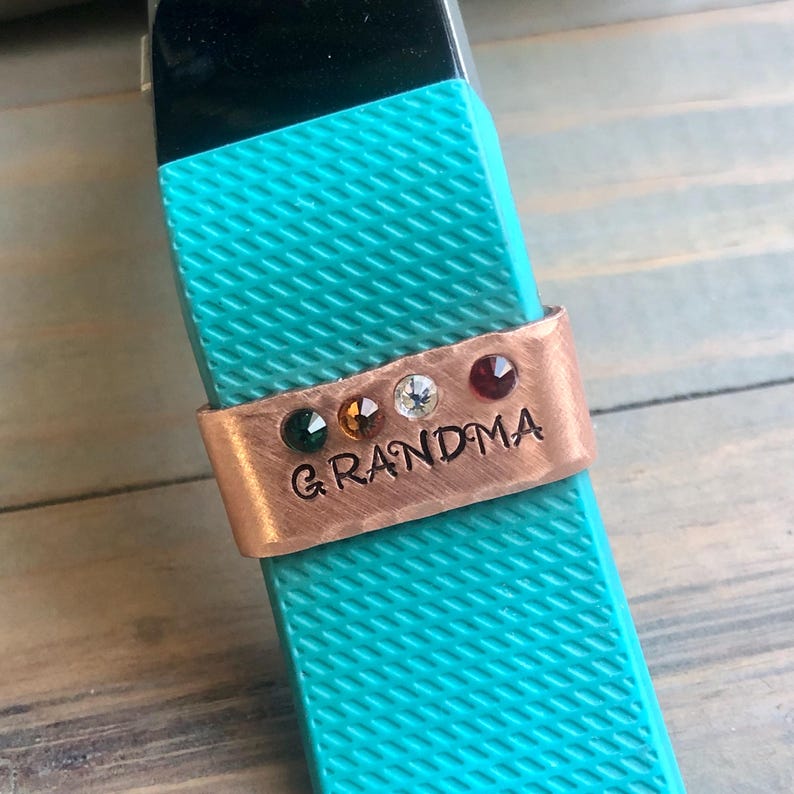 May include: Copper charm bracelet with the word "GRANDMA" engraved on it. The bracelet has five colorful gemstones.