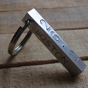 May include: A silver metal keychain with a rectangular tag engraved with "2160 BOSTON 21".