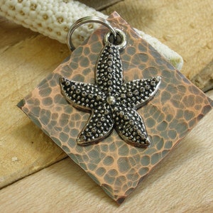 May include: A silver starfish charm on a hammered copper square pendant. The pendant has a rustic, distressed look.