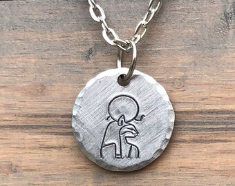 May include: Silver necklace with a round pendant featuring an engraved image of the Egyptian god Anubis.