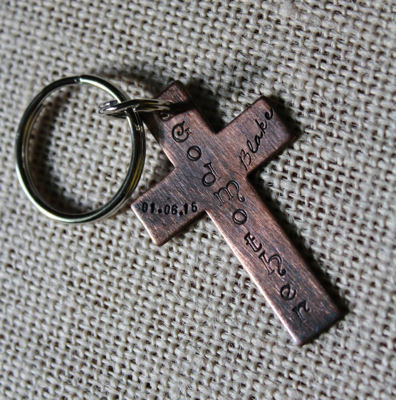 Pu&ograve; includere: Un portachiavi a forma di croce di colore rame con l'iscrizione "God Made Me" e "John Blake" sul davanti e "01.06.16" sul retro.